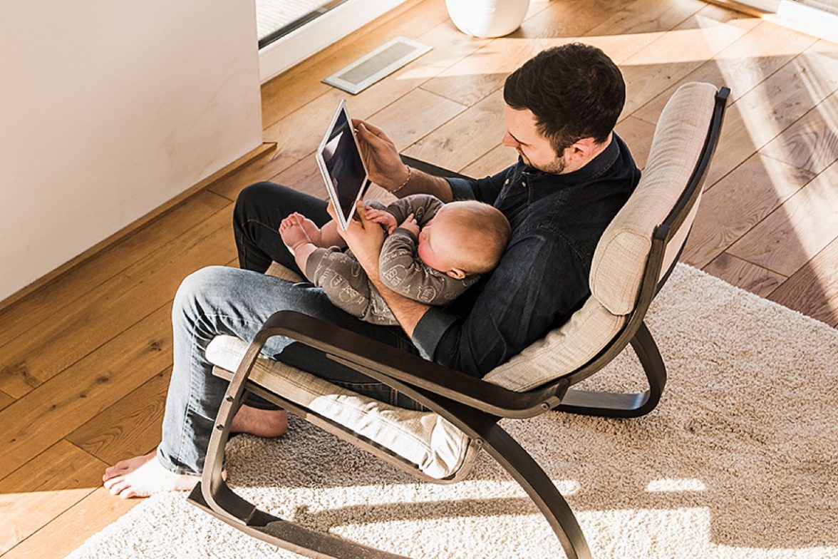 Padre en silla con bebe y tablet en mano