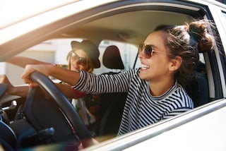Chica manejando un auto y sonriendo