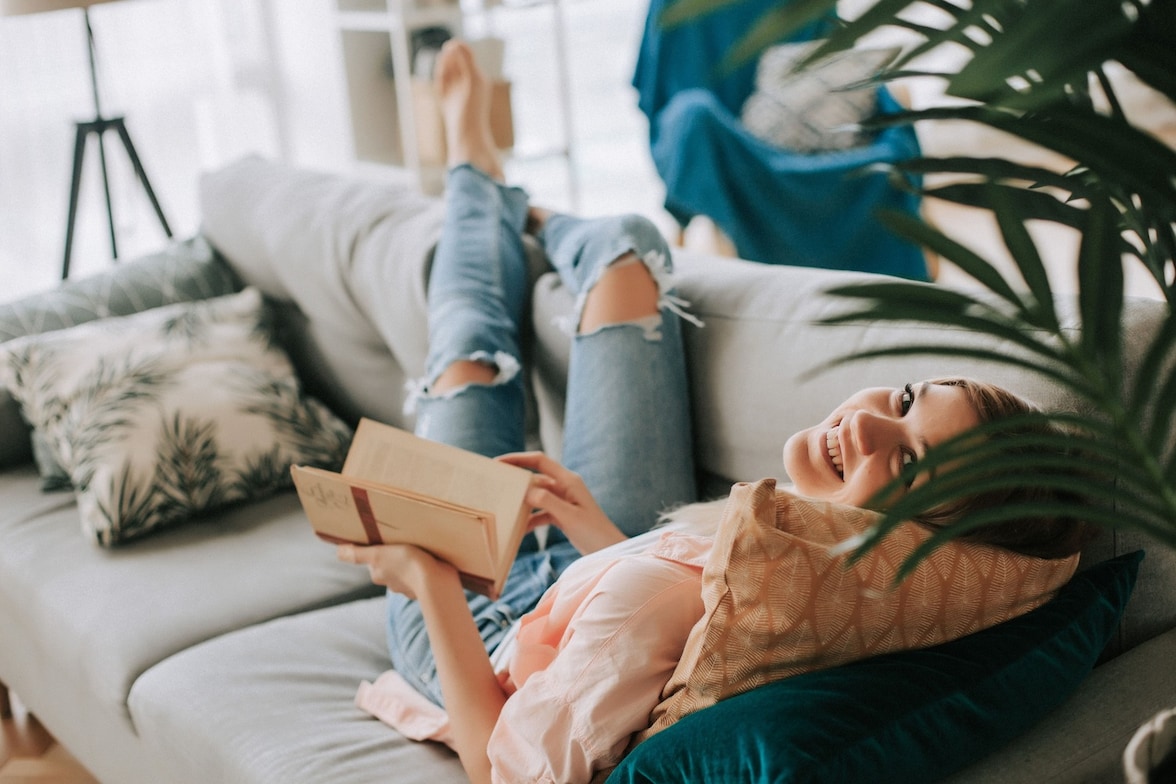 Mujer acostada en sillón con libro abierto